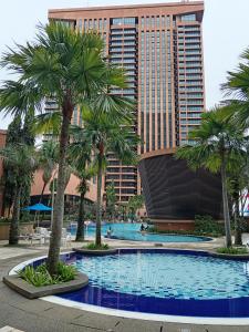 een zwembad met palmbomen en hoge gebouwen bij Eco suites at times square in Kuala Lumpur