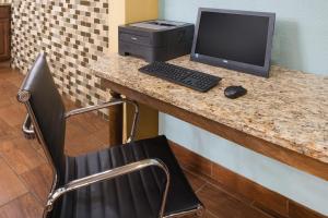 a desk with a computer and a monitor and a chair at Super 8 by Wyndham Warrensburg in Warrensburg