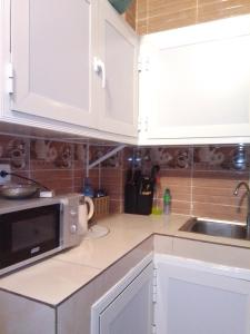 a kitchen with white cabinets and a microwave at Appartement fun in Dakar