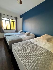 three beds in a bedroom with a blue wall at Hotel Mão de Fatima in Aparecida +63 photos