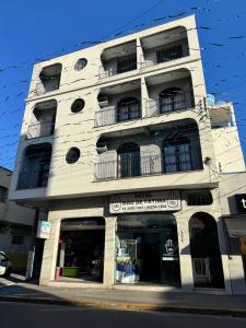 a tall white building with balconies on a street at Hotel Mão de Fatima in Aparecida