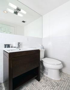 a white bathroom with a toilet and a sink at East Village Hotel in New York