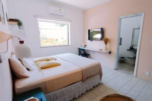 a white bedroom with a bed and a window at Casa mangarito - suítes in Ubatuba