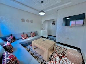 Una sala de estar con un sofá azul y una mesa. en A8 Getaway in Tamraght, Fiber Wi-Fi, 5 min to beach, en Tamraght Ouzdar