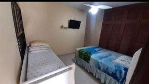 a small bedroom with a bed and a tv at Cantinho Charmoso no Guarujá in Guarujá +2 photos