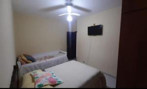 a room with a bed and a ceiling fan at Cantinho Charmoso no Guarujá in Guarujá