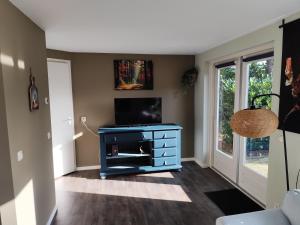 a living room with a tv and a blue dresser at Morning Glory, Huisje Dahlia in Beekbergen