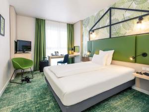 a hotel room with a large bed and a green wall at Mercure Hotel Hannover Mitte in Hannover