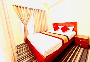 a bedroom with a bed with red pillows and a window at Himalayan Tranquil Stay in Burhānilkantha