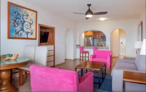 a living room with pink chairs and a table at Villa Del Palmar in Cabo San Lucas +4 photos