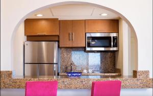 a kitchen with stainless steel appliances and pink chairs at Villa Del Palmar in Cabo San Lucas