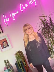a woman standing in a room with a neon sign at West Lodge - Buxton in Buxton