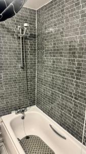 a bathroom with a bath tub with a shower at Modern 1-Bed Flat in Crystal Palace Sydenham in Sydenham