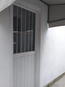 a white door with a window on a white building at Kitinete na praia do Mar Grosso Mobiliada in Laguna +2 photos