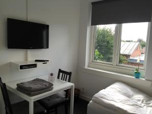 a bedroom with a desk with a bed and a television at Close But Quiet in Herlev