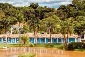 a blue house with palm trees and a flooded street at Quinta das Águas Hotel in Itapira