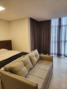 a living room with a couch in front of a bed at Loft 06 Vila Germânica Oktoberfest Blumenau in Blumenau