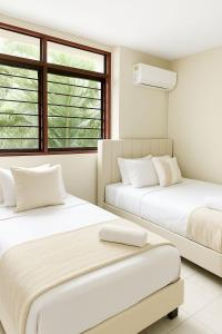 zwei Betten in einem Zimmer mit zwei Fenstern in der Unterkunft Hotel ladymar cartagena in Cartagena de Indias