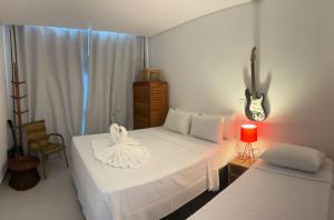 een slaapkamer met een wit bed met een gitaar aan de muur bij Morada de Gaudi in Porto Seguro
