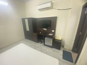 a room with a bed and a desk with a television at Collection O Jodhpur Railway Junction Formerly Paro Niwas in Jodhpur