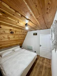 a bedroom with a white bed and wooden ceilings at Cabana JagerBerg Rosenau in Râşnov