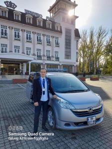 a man standing next to a silver car in front of a building at Happy Home in Kutaisi