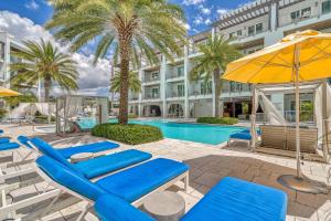 a pool with blue chairs and umbrellas next to a building at Texas Two Step by 30A Escapes in Rosemary Beach