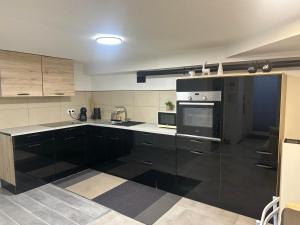 a large kitchen with black cabinets and appliances at Les Mirabelles in Ensisheim