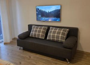 a couch in a living room with a tv on the wall at Chata SNOW in Valča