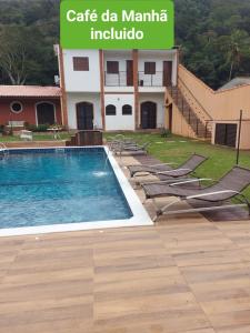 a swimming pool with lounge chairs in front of a building at Apart Hotel Guaiuba in Guarujá