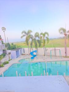 a swimming pool with a playground and palm trees at SK INN stays in Mahabalipuram
