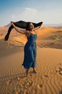 a woman in a blue dress standing in the desert at zonadima in Merzouga
