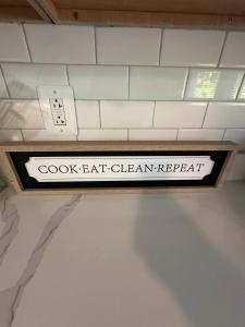 Un cartel en el techo que dice "cocinar, comer, limpiar, repetir". en Ranch Single Level Home near downtown Tinley Park, en Tinley Park