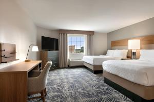 a hotel room with two beds and a desk and a television at Candlewood Suites Houston Space Center - Webster in Webster