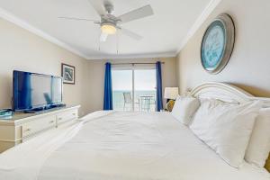 a bedroom with a white bed and a tv at Ocean House II 2602 in Gulf Shores +32 photos