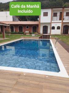 a swimming pool in front of a building with the words cafe da manta in at Apart Hotel Guaiuba in Guarujá