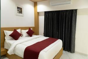 a bedroom with a large bed with red pillows at Hotel Stayzi Inn in Navi Mumbai
