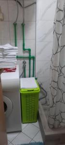 a bathroom with a green trash can next to a toilet at Studio apartman City Centre Rogatica in Rogatica