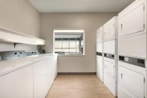 a white kitchen with white cabinets and a window at Candlewood Suites Houston Space Center - Webster in Webster