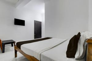 a white bedroom with a bed and a table at Hotel O Shree Guest House in Khandagiri +7 photos