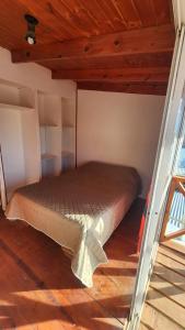 a bed in a small room with a wooden ceiling at Los cabos in Puerto San Julian