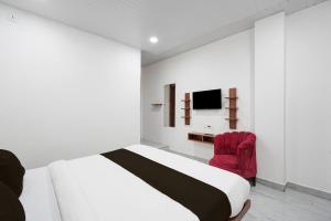 a white bedroom with a bed and a red chair at Hotel O Royal Krishna in Gorakhpur