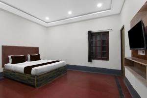 a bedroom with a bed and a flat screen tv at Hotel O Smriti Villa in Ballygunge