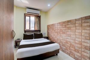 une chambre avec un lit et un mur de briques dans l'établissement Hotel O Gold Coast, à Mumbai
