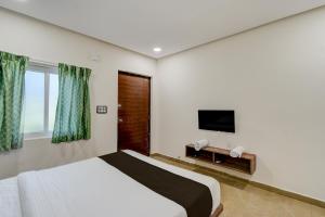 Un dormitorio con una cama y un televisor de pantalla plana. en Hotel O EVA, en Gundipet