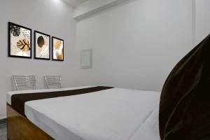 a bedroom with a white bed with four pictures on the wall at HOTEL O BABA PREM HOTEL in Bihta