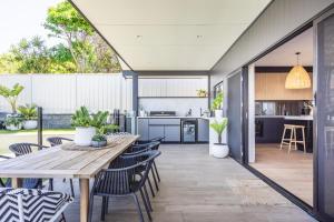 an open kitchen and dining room with a wooden table and chairs at Caves Coastal Escape in Swansea