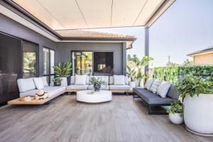 an outdoor patio with white furniture and plants at Caves Coastal Escape in Swansea