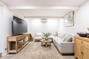 a living room with a couch and a flat screen tv at Caves Coastal Escape in Swansea