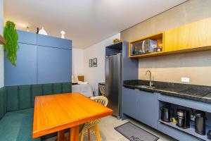 a kitchen with a wooden table and a kitchen with blue cabinets at Studio com 2 Camas de Casal e Garagem - EIX0705 in Curitiba